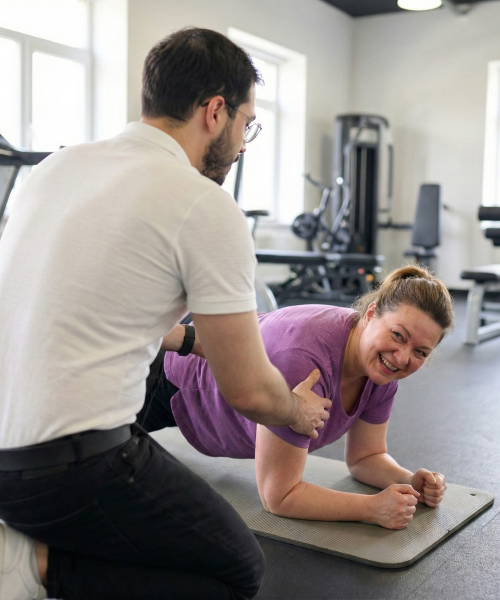 Personal Trainer Wladi gibt einem Kunden im roten T-Shirt Hilfestellung beim TRX-Training zur Stärkung der Rückenmuskulatur.